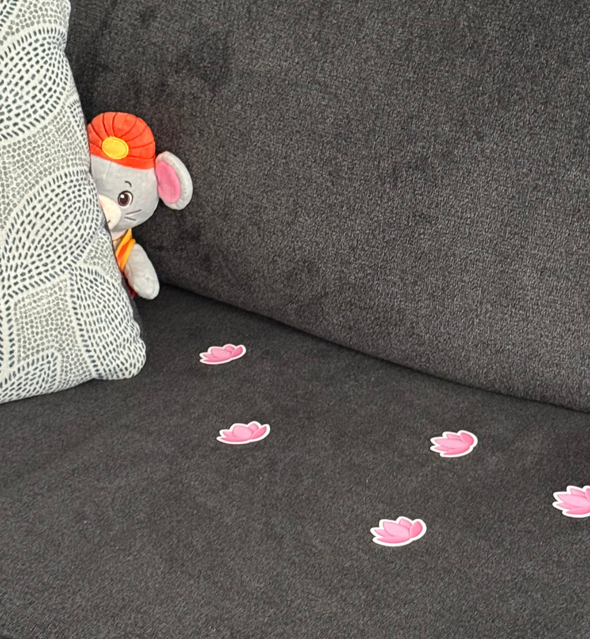 A trail of lotus footprint stickers lead to Mooshika peeking out from behind a couch pillow